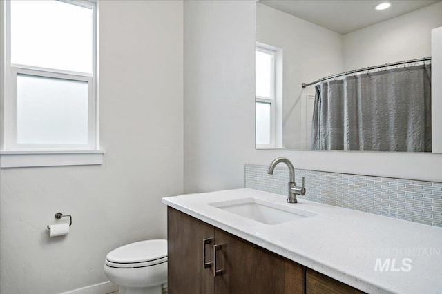 bathroom with toilet, backsplash, recessed lighting, baseboards, and vanity