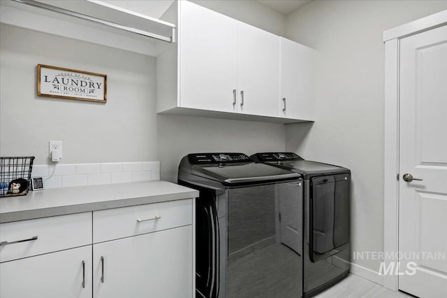 clothes washing area featuring cabinet space, independent washer and dryer, and baseboards