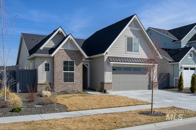 view of front of house featuring a standing seam roof, a garage, brick siding, and driveway