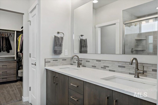 full bathroom featuring a shower stall, double vanity, backsplash, and a sink