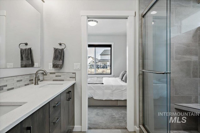 ensuite bathroom featuring a sink, decorative backsplash, a stall shower, and ensuite bath