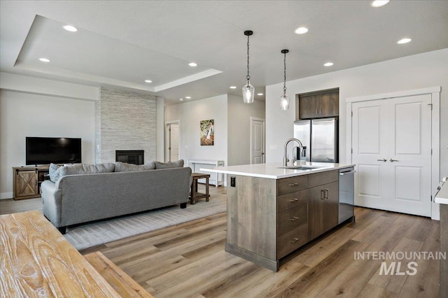 kitchen with a sink, a tray ceiling, stainless steel appliances, light countertops, and dark brown cabinets