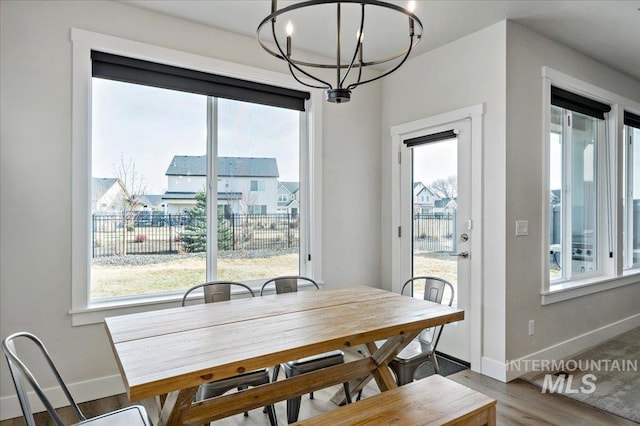 dining area featuring wood finished floors, a wealth of natural light, and a chandelier