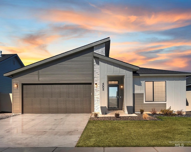 view of front facade featuring an attached garage, concrete driveway, board and batten siding, and a front yard