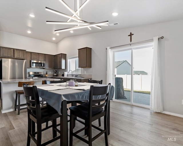 kitchen with stainless steel appliances, light countertops, visible vents, dark brown cabinetry, and light wood-type flooring