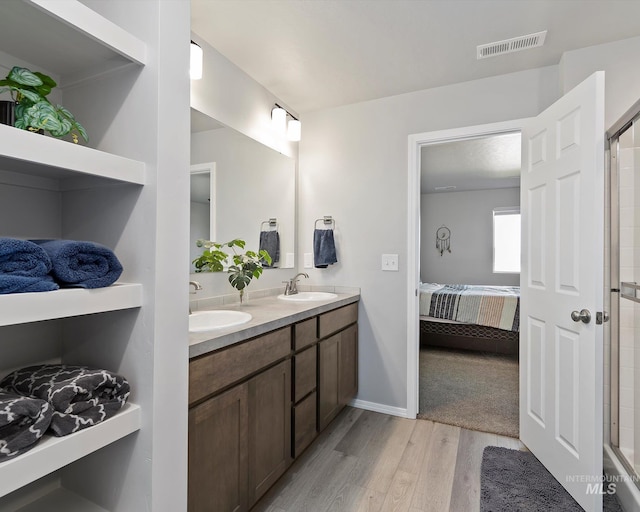 full bathroom featuring ensuite bathroom, wood finished floors, a sink, and visible vents