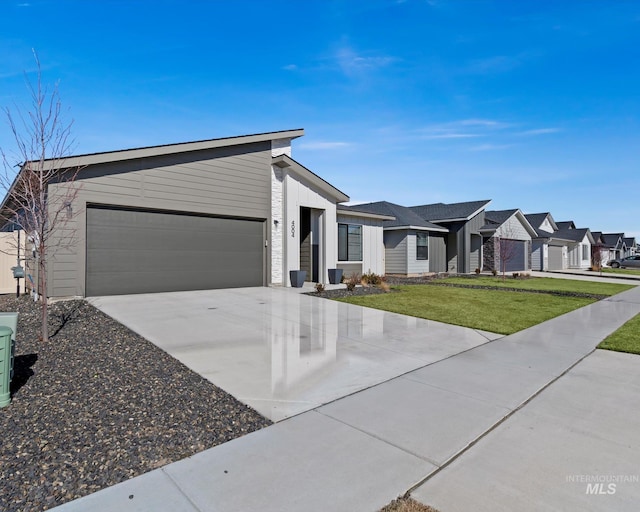 view of front facade featuring an attached garage, driveway, a front yard, and a residential view