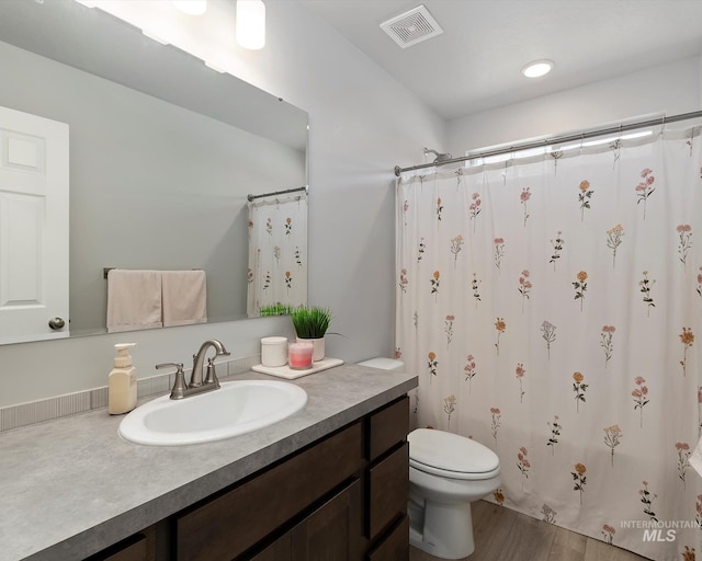 full bathroom with visible vents, a shower with shower curtain, toilet, wood finished floors, and vanity