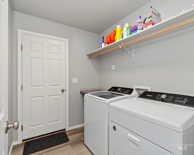 clothes washing area with light wood-type flooring, washing machine and dryer, laundry area, and baseboards