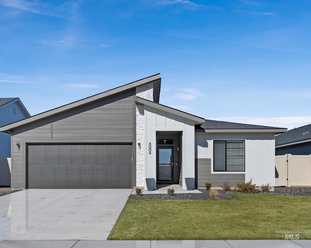 view of front facade featuring an attached garage, concrete driveway, board and batten siding, and a front yard