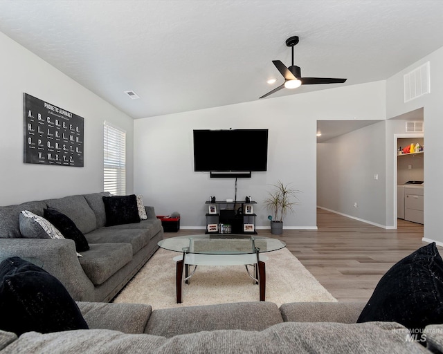 living area featuring vaulted ceiling, separate washer and dryer, wood finished floors, and visible vents