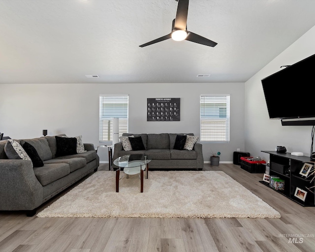 living room featuring a wealth of natural light, wood finished floors, and visible vents