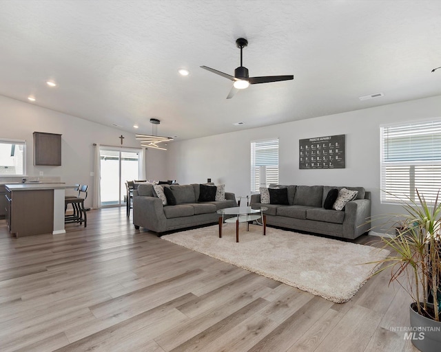 living area featuring visible vents, light wood-style flooring, and a ceiling fan