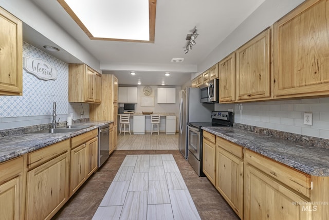 564 Blue Lakes Blvd, Twin Falls, ID 83301 - kitchen featuring stainless steel appliances, a sink, tasteful backsplash, light brown cabinetry, and a skylight