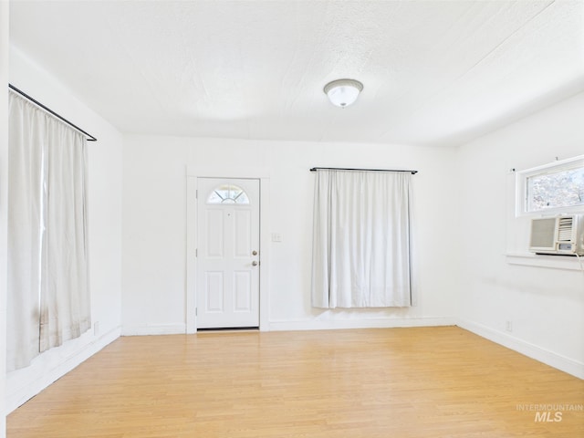foyer featuring baseboards, plenty of natural light, cooling unit, and light wood-style flooring