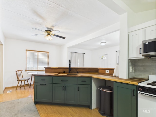 kitchen with white electric range oven, tasteful backsplash, a sink, green cabinetry, and butcher block countertops