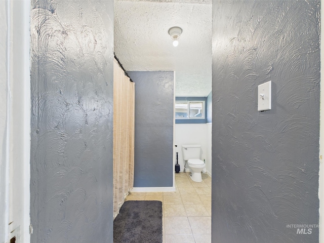 bathroom featuring tile patterned flooring, baseboards, and toilet