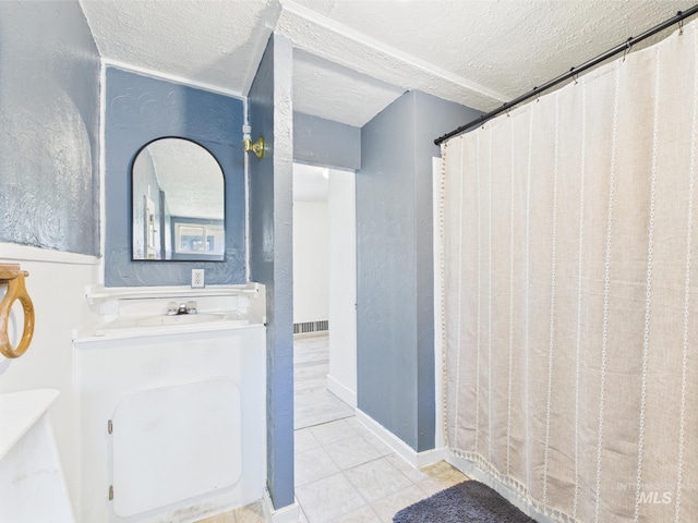 full bathroom featuring a sink, tile patterned floors, a textured ceiling, and visible vents
