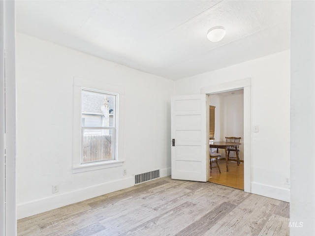 spare room featuring visible vents, baseboards, and wood finished floors