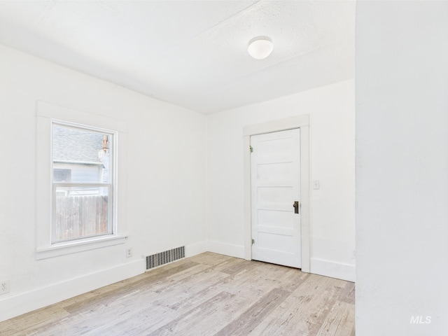 unfurnished room with baseboards, wood finished floors, and visible vents