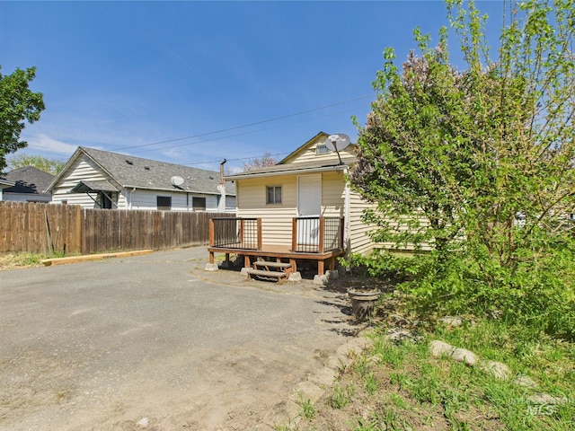 rear view of house with fence and a deck