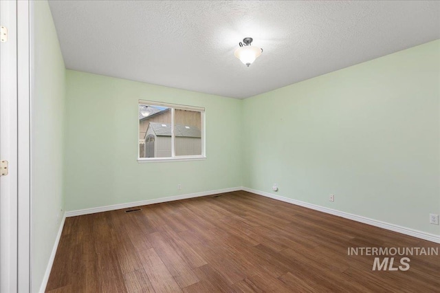 empty room with hardwood / wood-style flooring and a textured ceiling