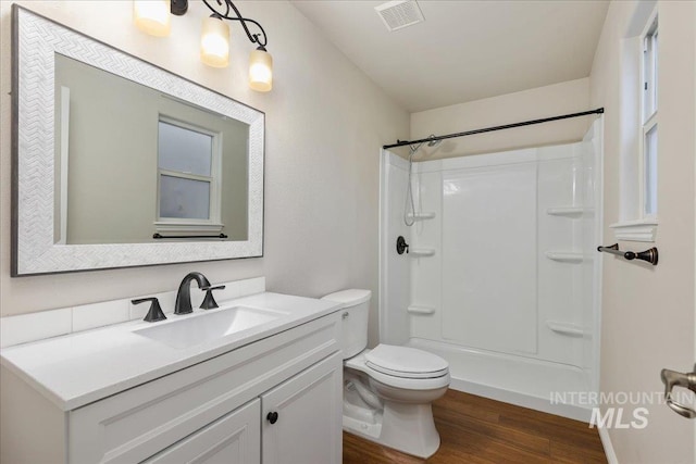 bathroom with a shower, toilet, wood-type flooring, and vanity