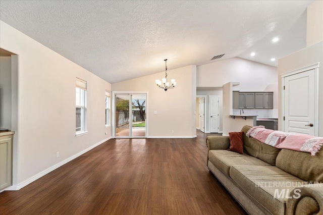 living room featuring an inviting chandelier, vaulted ceiling, dark hardwood / wood-style flooring, and a textured ceiling