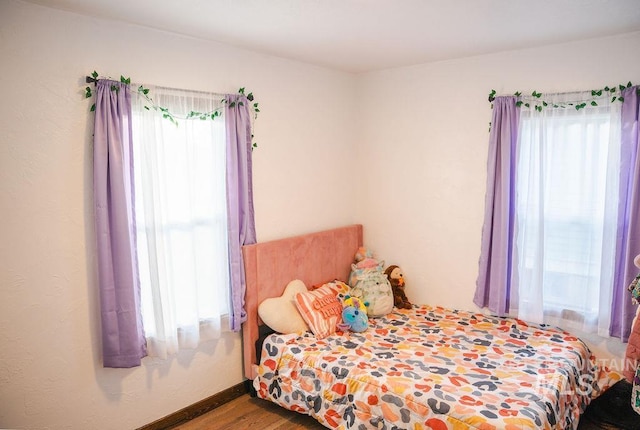 bedroom with multiple windows and hardwood / wood-style flooring