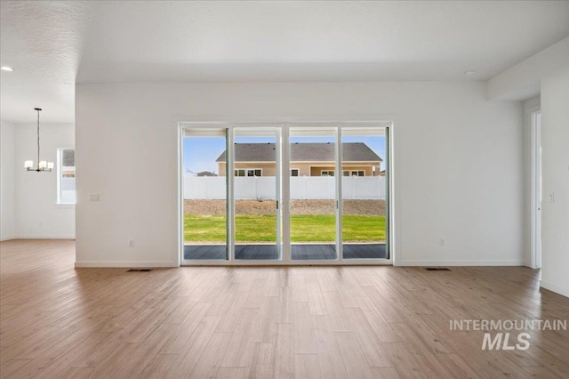 8828 S Waterclover Way, Meridian, ID 83642 - spare room featuring a chandelier, healthy amount of natural light, wood finished floors, and baseboards