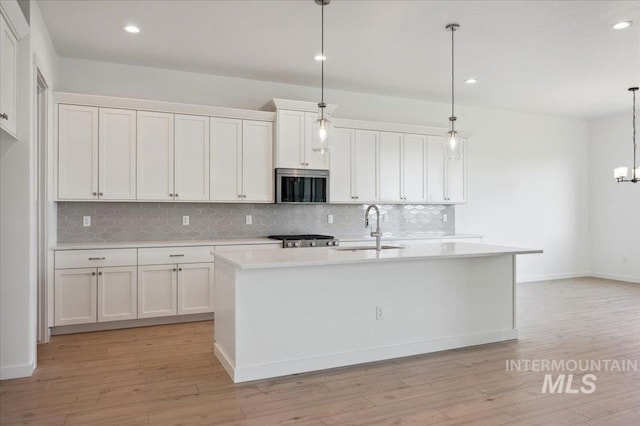 8828 S Waterclover Way, Meridian, ID 83642 - kitchen featuring backsplash, a sink, light countertops, stainless steel microwave, and recessed lighting