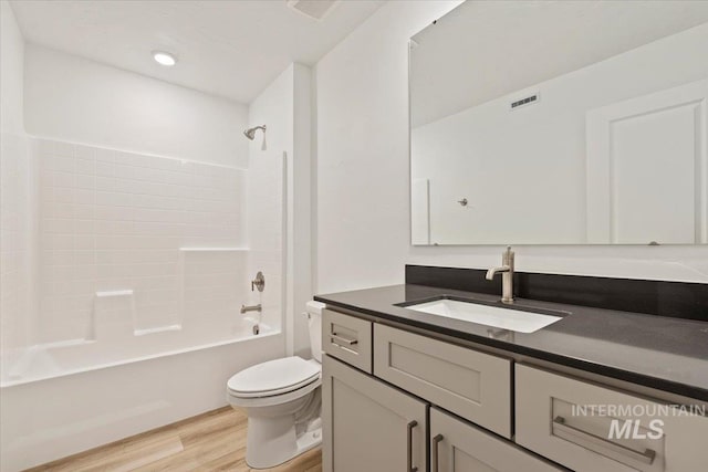 full bathroom featuring hardwood / wood-style floors, vanity, toilet, and shower / bathtub combination