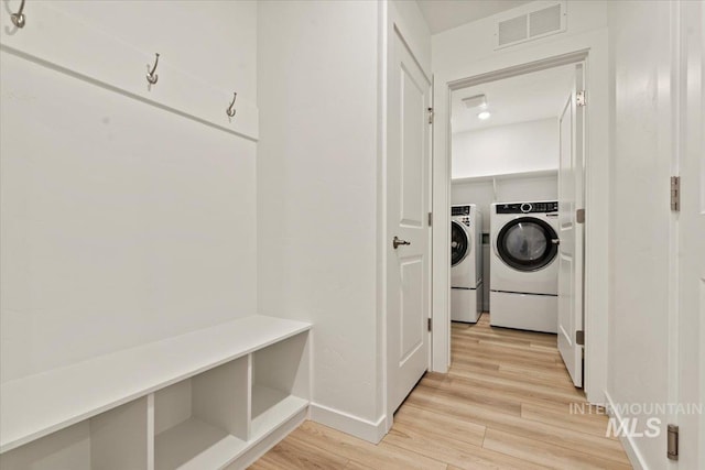 clothes washing area with separate washer and dryer and light hardwood / wood-style floors