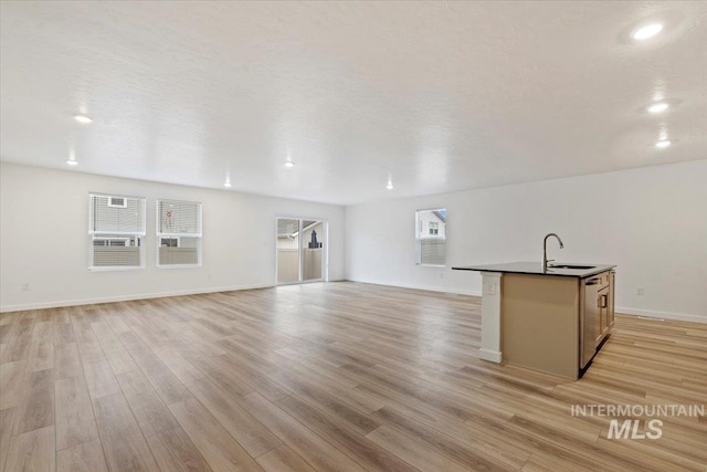 unfurnished living room with a textured ceiling, light hardwood / wood-style floors, and sink