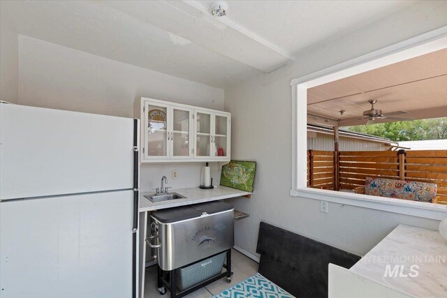 9740 W Shields Ave, Boise, ID 83714 - kitchen with freestanding refrigerator, white cabinetry, ceiling fan, glass insert cabinets, and light countertops
