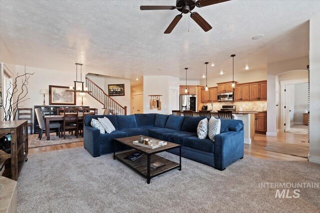 9740 W Shields Ave, Boise, ID 83714 - living room featuring a ceiling fan, a textured ceiling, stairway, arched walkways, and light wood-type flooring