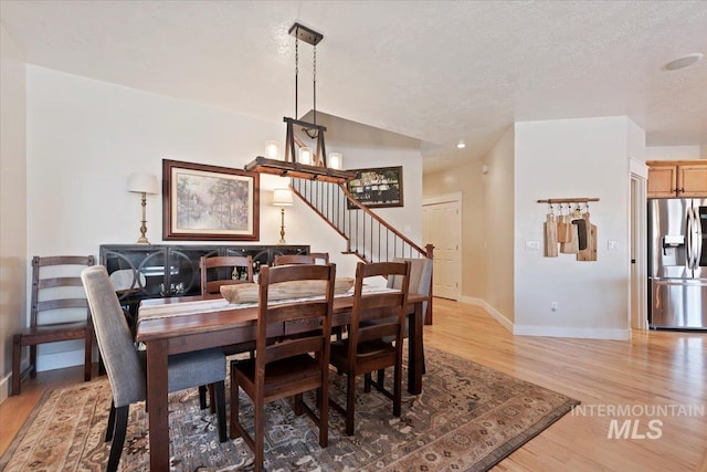 9740 W Shields Ave, Boise, ID 83714 - dining area featuring baseboards, light wood-style flooring, a chandelier, stairs, and a textured ceiling