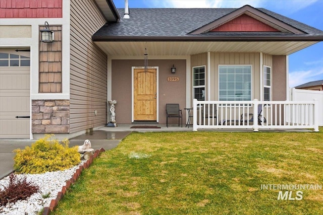 1095 Starlight Loop, Twin Falls, ID 83301 - view of exterior entry with a porch, a yard, a shingled roof, and a garage