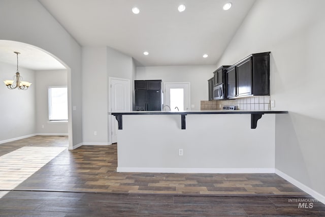 1095 Starlight Loop, Twin Falls, ID 83301 - kitchen with a kitchen bar, arched walkways, stainless steel microwave, a chandelier, and dark wood-style flooring