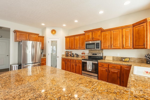 kitchen with sink, a textured ceiling, and appliances with stainless steel finishes