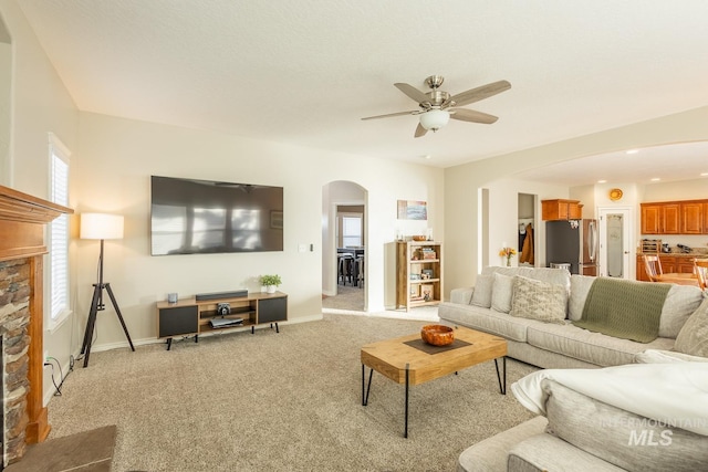 carpeted living room featuring a fireplace and ceiling fan