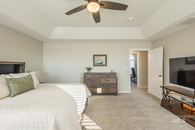 bedroom featuring light carpet, a raised ceiling, and ceiling fan