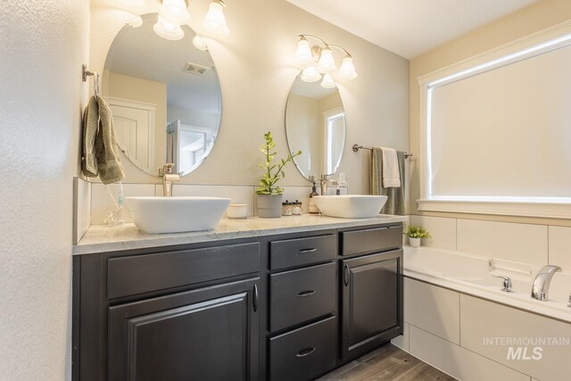 bathroom with vanity, wood-type flooring, and a tub to relax in