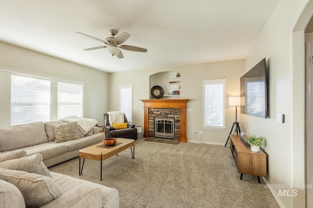 carpeted living room featuring ceiling fan, a textured ceiling, and a fireplace