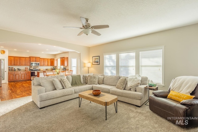 living room featuring ceiling fan, a textured ceiling, and light hardwood / wood-style flooring