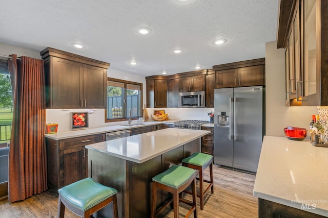 4400 W Pasadena Dr Unit 38, Boise, ID 83705 - kitchen featuring stainless steel appliances, a sink, a kitchen bar, dark brown cabinetry, and light countertops
