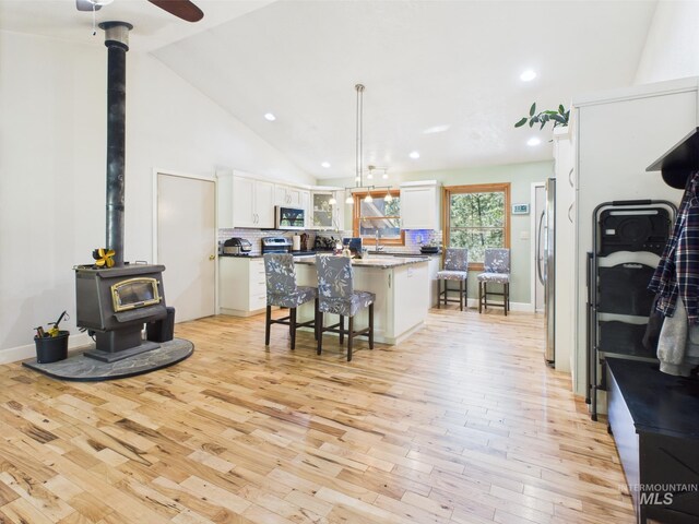 9 Pond Overlook, Idaho City, ID 83631 - kitchen with a wood stove, light wood-type flooring, decorative backsplash, white cabinets, and appliances with stainless steel finishes