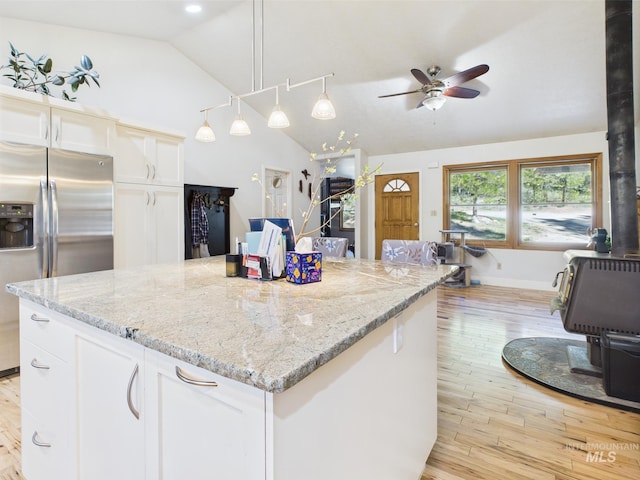 9 Pond Overlook, Idaho City, ID 83631 - kitchen with a ceiling fan, stainless steel refrigerator with ice dispenser, white cabinetry, a wood stove, and vaulted ceiling