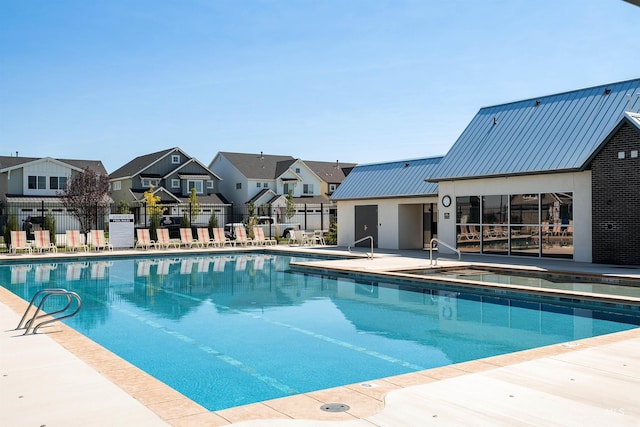 community pool featuring a residential view, fence, and a patio area