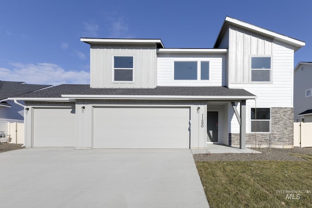 view of front of property with an attached garage, board and batten siding, fence, and driveway